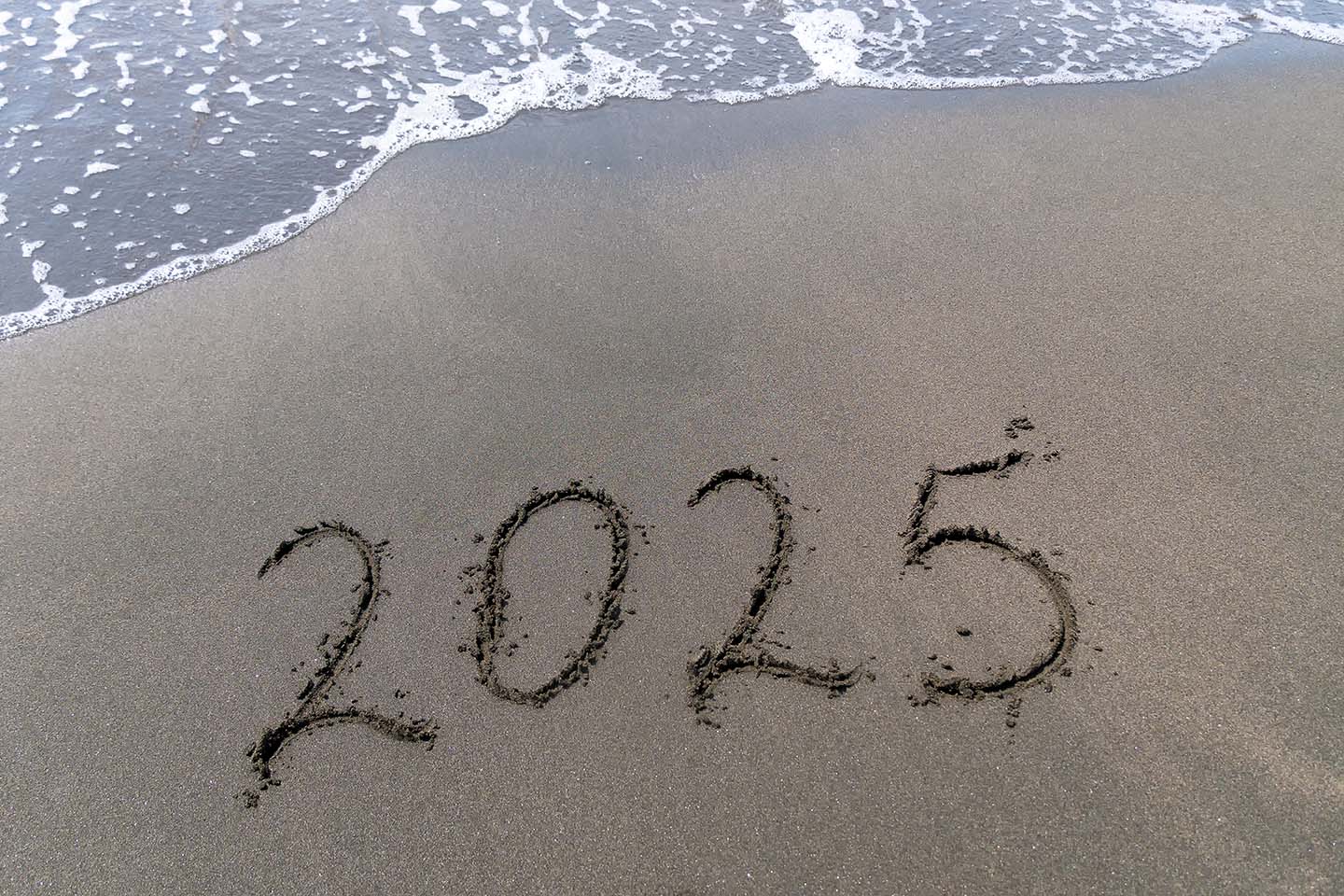 Text Happy New Year 2025 On A Sandy Sea Beach With A Small Wave.